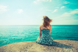 A young woman is sitting on a pier by the ocean